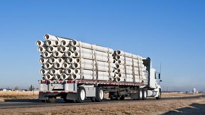 Flat bed trucking company driver hauling pipes